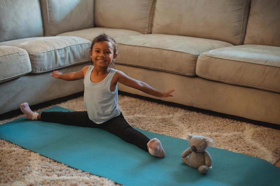 Cheerful little girl laughing while doing a yoga stretch on a mat