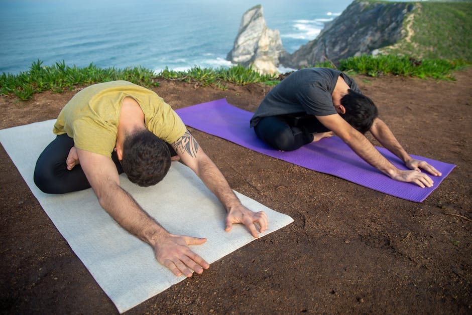 Two children doing a downward-facing dog pose on yoga mats outdoors